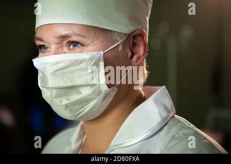 Tired nurse doctor in protective mask and cap against coronavirus type Covid 19. Close-up. Stock Photo