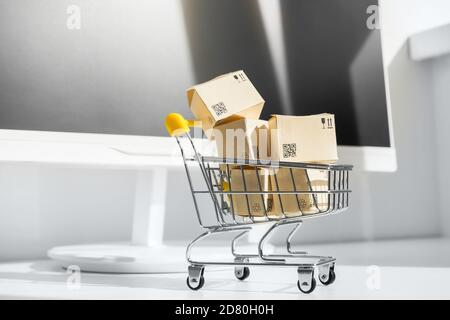 Online shopping concept. Small shopping cart with many paper boxes on the desktop. Black friday sale. Buy in one click Stock Photo