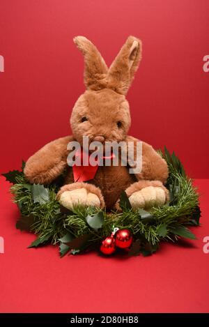 Toy Rabbit sitting in a Christmas garland in portrait Stock Photo