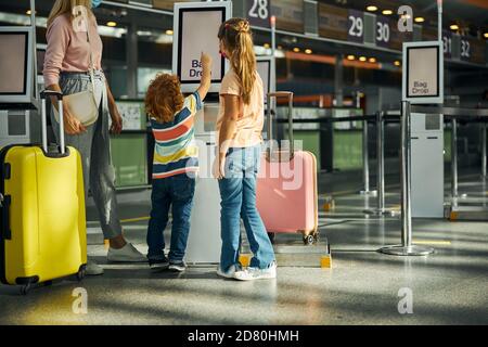 Curious boy touching a screen of a bag drop kiosk Stock Photo