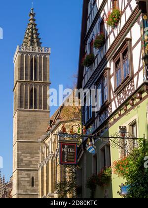 A tower of Rothenburg ob der Tauber St. Jakob Church by a timber-framed house Stock Photo