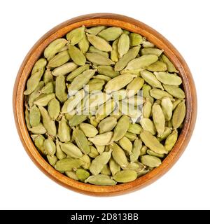 Green cardamom pods in a wooden bowl. True cardamom, processed pods and seeds of Elettaria cardamomum, sometimes cardamon or cardamum, used as a spice Stock Photo