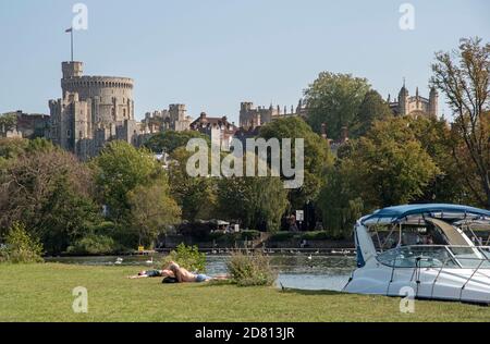 Windsor, Berkshire, England, UK. 2020.  Tourists and boats along the riverbank of the River Thames at Windsor with a backdrop of Windsor Castle. Stock Photo