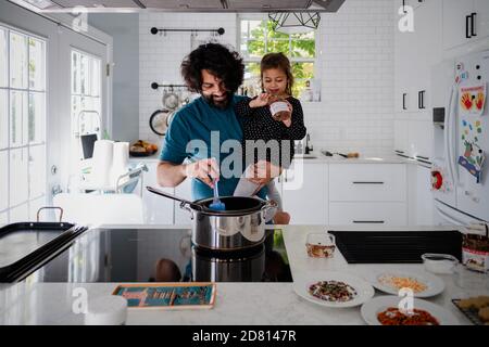 father and daughter baking holiday cookies in white kitchen Stock Photo