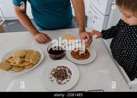 father and daughter decorating halloween cookies together Stock Photo
