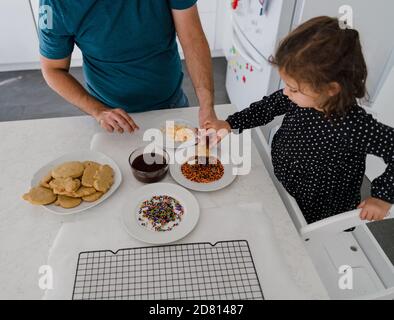father and daughter decorating holiday cookies together Stock Photo