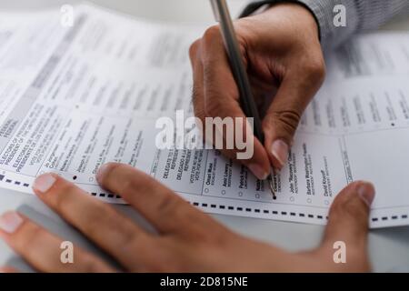 close up of man's hands completing absentee ballot for election Stock Photo