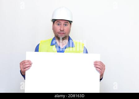 Close-up Engineer man wearing a helmet and reflector vest, standing and holding a billboard. White background. Stock Photo