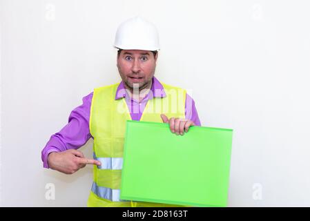 curious surprised architect in a construction helmet holding a folder, free place mock up banner.Studio shoot. Stock Photo