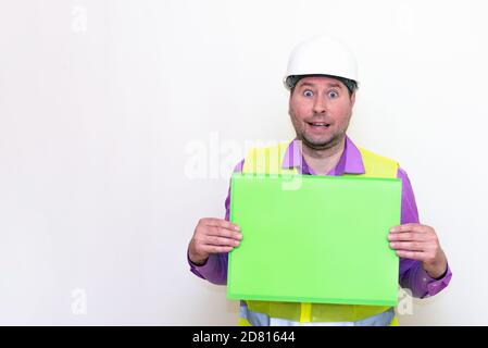 curious surprised architect in a construction helmet holding a folder, free place mock up banner.Studio shoot. Stock Photo