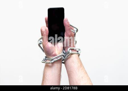 Close up Man holding smartphone with metal chain on white studio background. concept security Stock Photo