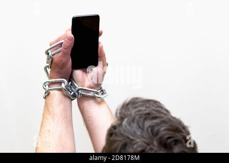 Close up Man holding smartphone with metal chain on white studio background. concept security Stock Photo