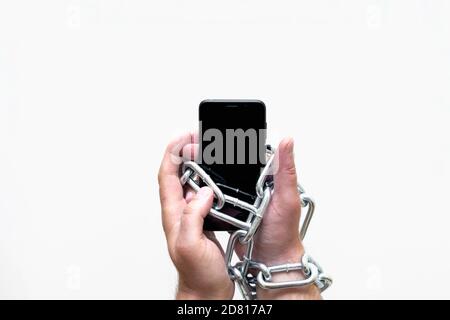 Close up Man holding smartphone with metal chain on white studio background. concept security Stock Photo