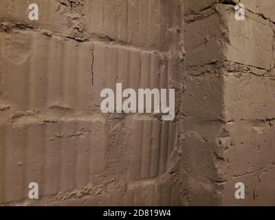 Corner of old wall. Uneven surface of cracked grungy brick wall closeup. Rough cement joints and ribbed textures of brickwork masonry Stock Photo