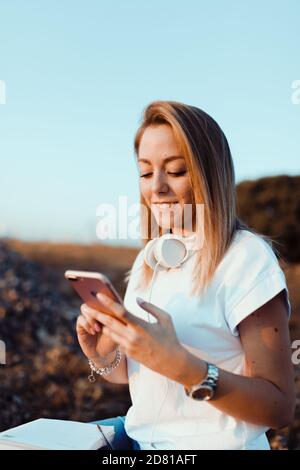 Young woman taken notes on her smartphone in the field Stock Photo