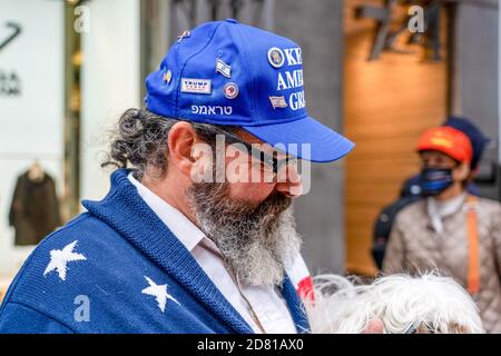 A president Trump supporter seen with a pet as participants gather across from Trump Tower during the protest.Pro President Trump supporters march along 5th avenue with caravan of cars and huge Trump blue, white, black flag.  They march from Trump Tower on 5th Avenue to 42nd Street and from there to Times Square where they met with counter protesters.  The Anti-Trump protesters hurled insults and objects like paint-filled bottles and eggs. There were lots of scuffles between those two groups and police made more than a dozen arrests. Stock Photo