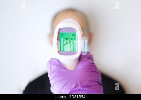 Hand holding a digital thermometer measuring a man temperature Stock Photo