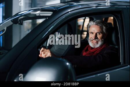 Happy stylish senior man with grey hair and mustache is in the modern car Stock Photo