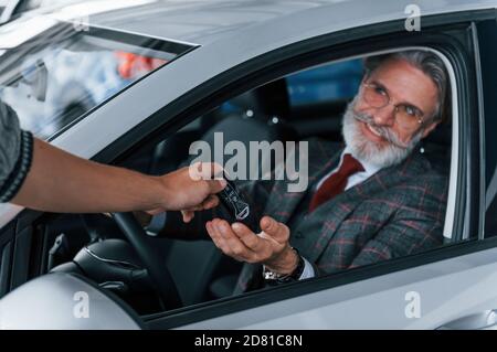 Modern stylish senior man with grey hair and mustache is in the modern car Stock Photo