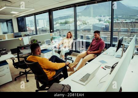 Diverse small group of colleagues relaxing during lunch break discussing weekend plans in office Stock Photo