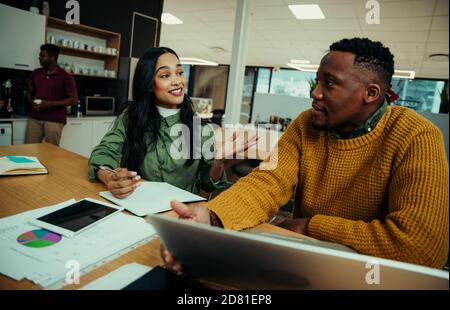 Indian woman correcting business man while discussing documents researching on laptop in foyer Stock Photo