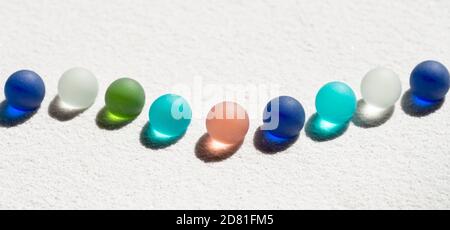Colorful marbles on white sand background Stock Photo