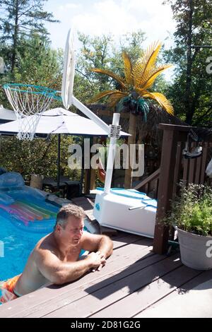 Man catching the sun in his home swimming pool resting on the side. Downers Grove Illinois IL USA Stock Photo