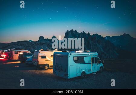 Row of Camper Vans Motorhomes on the Ridge at Night. Mountain RV Camping in the Italian Dolomites. Starry Summer Sky. Stock Photo