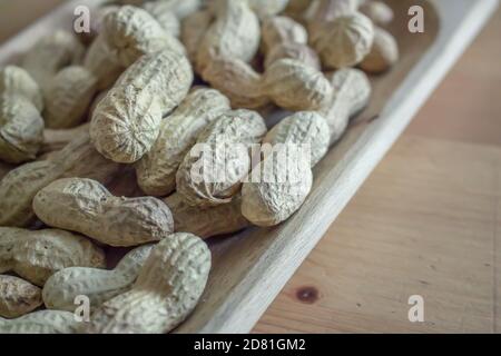 Some whole American peanuts with shell inside a rectangular wooden tray Stock Photo