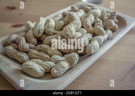 Some whole American peanuts with shell inside a rectangular wooden tray Stock Photo