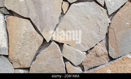 Stone pieces mosaic wall background. Rough stone textured background. Brickwork backdrop. Stone masonry wall surface closeup Stock Photo