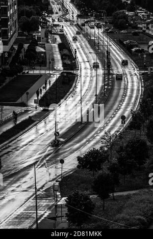 Black and white image of wide street in city wet and shining after rain Stock Photo