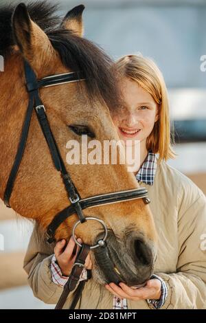 Smiling little ginger girl posing with her horse. Smiling at tha camera. Stock Photo