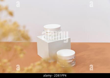 Bottles of cosmetic cream on podium over brown background in sunlight Stock Photo