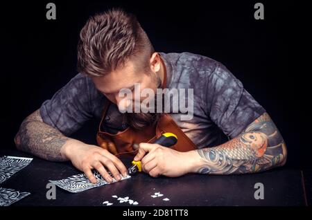 Handyman performing leatherwork on a new product piece in workplace Stock Photo