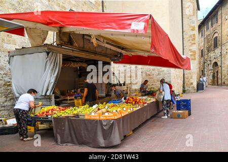 People shopping at a fruits and vegetables market stall in the old town of San Gimignano, Unesco World Heritage Site, Siena, Tuscany, Italy