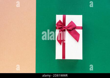 Gift in a box on beige and green combo background. Holiday concept. Top view, flat lay, copy space. Stock Photo