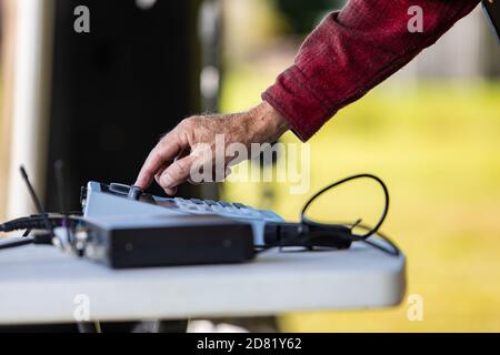 Selective focus of hands of male dj mixing sound and speaker with electrical sound equalizer by adjusting system during cultural fiesta at venue Stock Photo