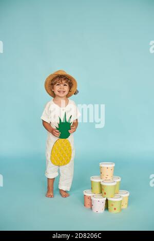 Little boy in straw hat posing in photo studio on blue background. Stock Photo