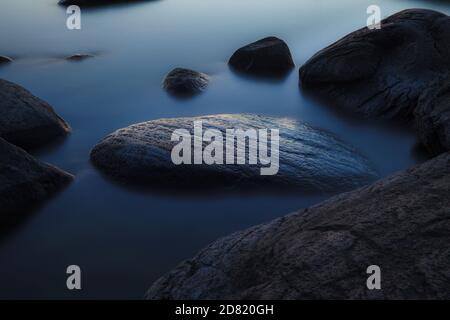 Stones on sea coast. Sunset over the sea. Deep blue color of summer late sunset. Long exposure Stock Photo