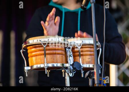 Selective focus of young male hands playing native sacred drum with hands and mic facing towards instrument during cultural fiesta Stock Photo