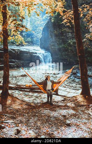 woman laying on hammock with view of autumn waterfall Stock Photo