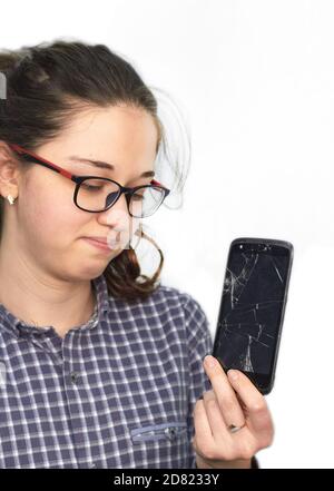 Broken glass screen smartphone in hand of upset girl. Stock Photo