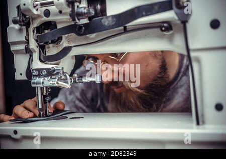 Currier of leather cutting out leather shapes for a new product in his studio Stock Photo