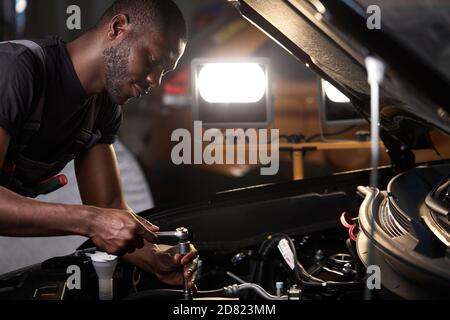 auto mechanic male use wrench and other tools for fixing a car engine, working alone Stock Photo