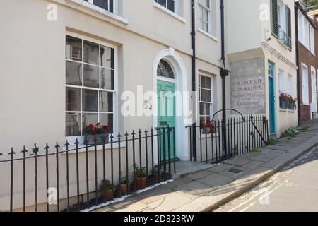 Georgian house and doorway, with old sign for a painter and glazier painted on an old shop wall, Hastings Old Town, East Sussex, UK Stock Photo