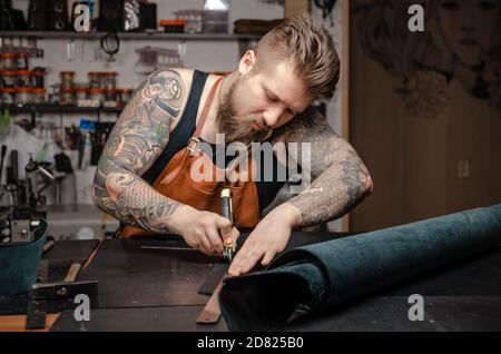 Leather Currier creating new leatherwork in his tanner shop Stock Photo