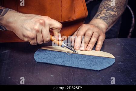 Artisan performing leatherwork on a new product piece Stock Photo