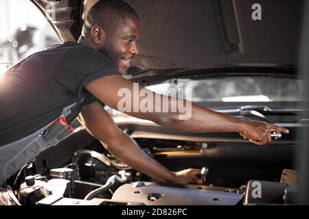 repairing in action. hardworking guy employee in uniform works in the automobile salon, confident auto mechanic is professional worker of service Stock Photo