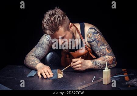 Craftsman working with leather cuts out leather goods in the tanner shop Stock Photo